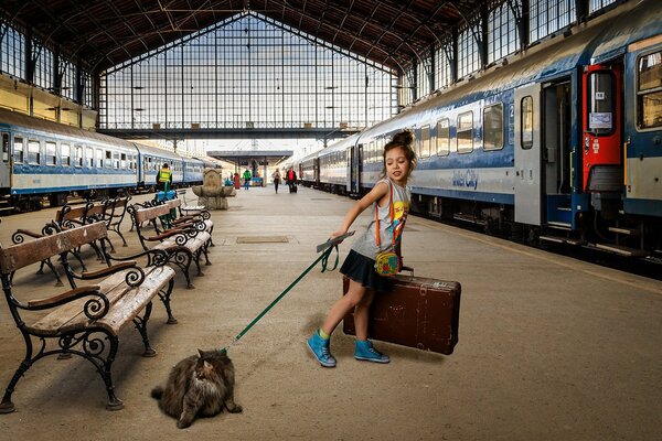 Niña con gato con correa en la plataforma frente al tren