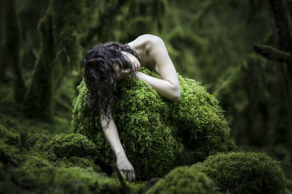 Pâle de la jeune fille dans la forêt sur la mousse