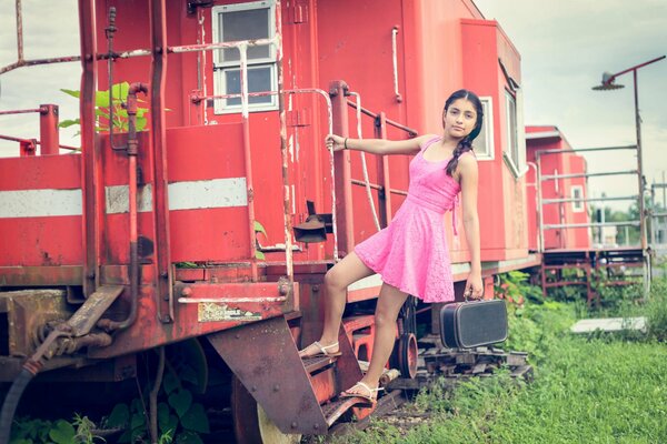 A girl with a small suitcase climbs into an old carriage