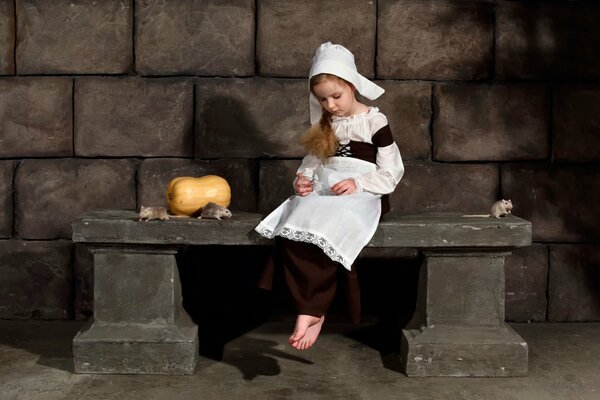 A little girl is sitting with a pumpkin