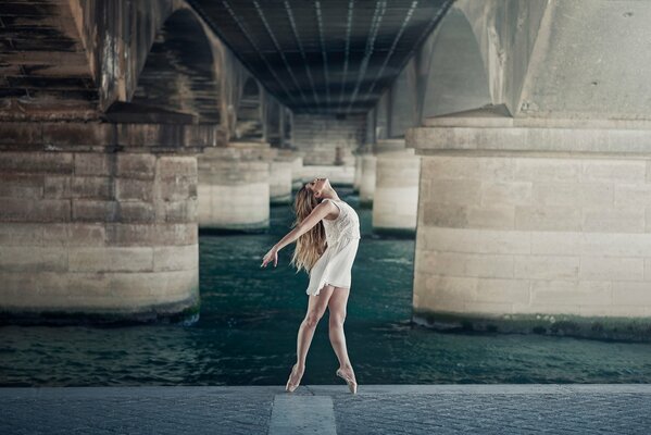 Graceful ballerina dancing under the bridge