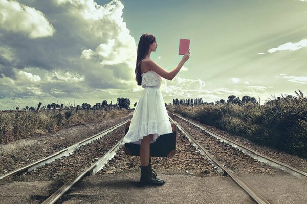 Fille sur le chemin de fer avec un livre dans les mains