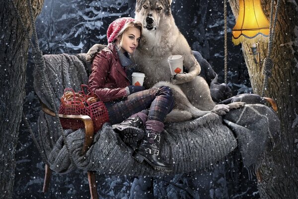 Caperucita roja con un lobo y una taza de café en un columpio en invierno