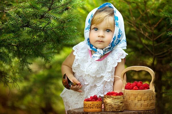 Ein Mädchen in einem Taschentuch sammelt Himbeeren