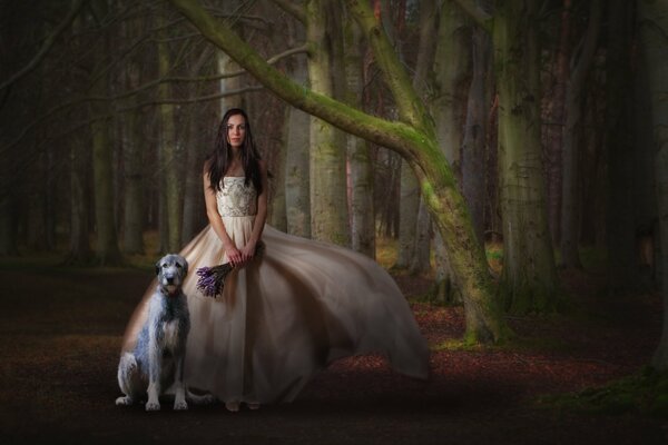 La jeune fille dans une belle robe avec un bouquet de fleurs et un petit chien