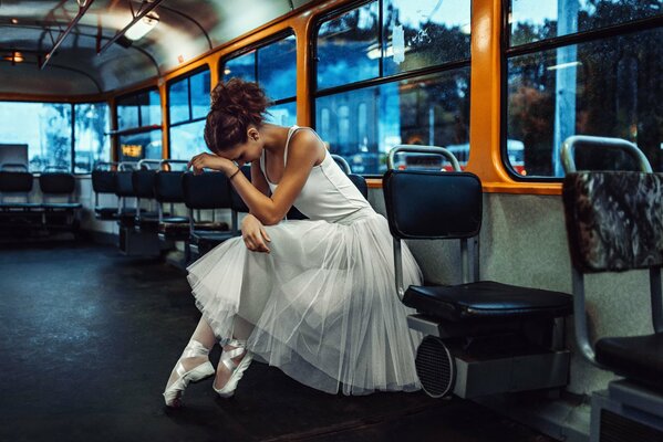 A ballerina in a tutu and pointe shoes rides a bus