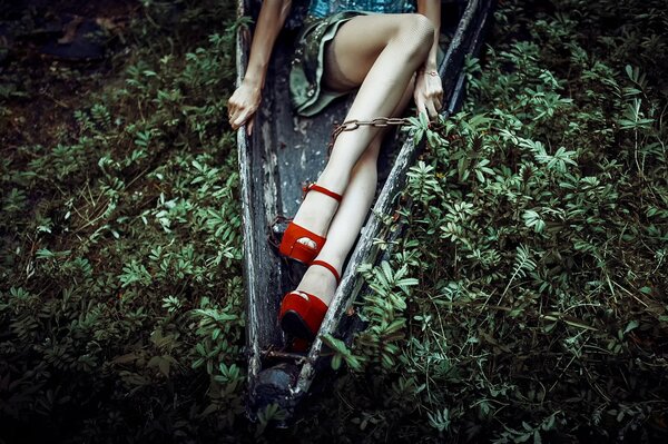 Gambe femminili in tacchi rossi e catene