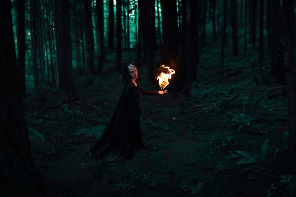 Девушка с огнем в темном лесу