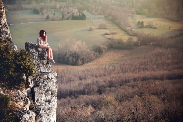 Red-haired girl sitting on a rock