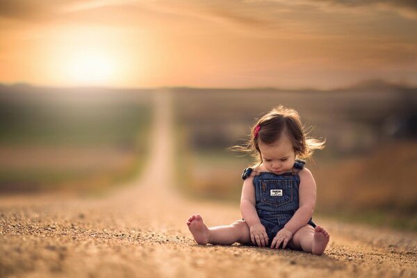 Une petite fille est assise sur la route