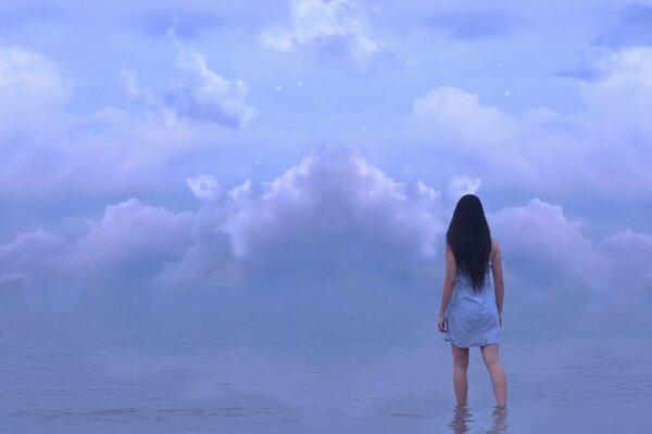 Ragazza in piedi in acqua sotto le nuvole