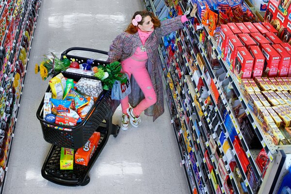 Fille sur les étagères du magasin avec chariot