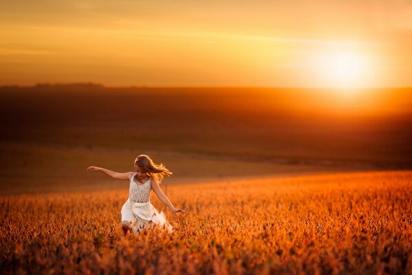 Ragazza in abito bianco corre un campo pop su uno sfondo di sole