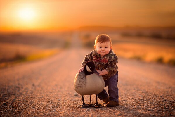 Camino soleado con un niño abrazando un pájaro