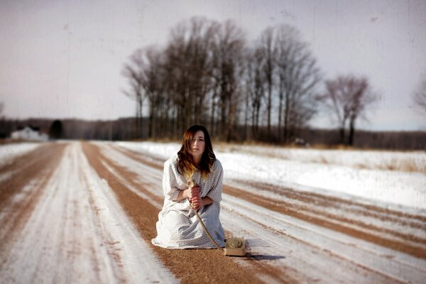 A girl with a wired phone on a snowy road