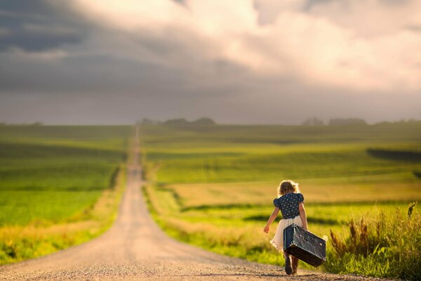 A girl with a suitcase is walking along the road