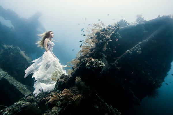 A girl climbs on a rock in the water