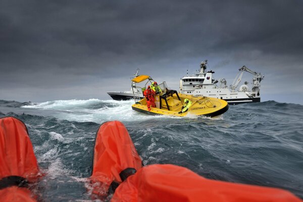 Sytuacja ratowania pasażerów jachtu przez ratowników na łodzi na Oceanie