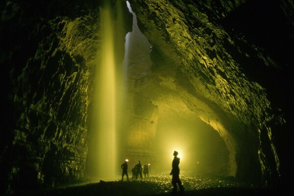 Zdjęcia ludzi w ogromnej ciemnej jaskini