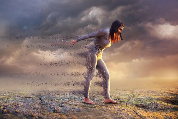 A girl in the process of disintegration against a background of gray clouds