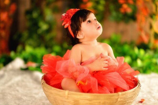 Una bambina in un vestito rosso si siede in un karzin