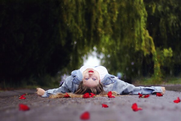 The girl is lying on the road in flower petals