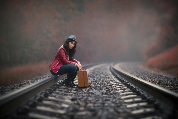 A girl is waiting with suitcases on the rails