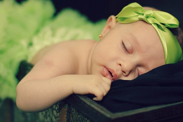 Sweet girl with a green bow is sleeping