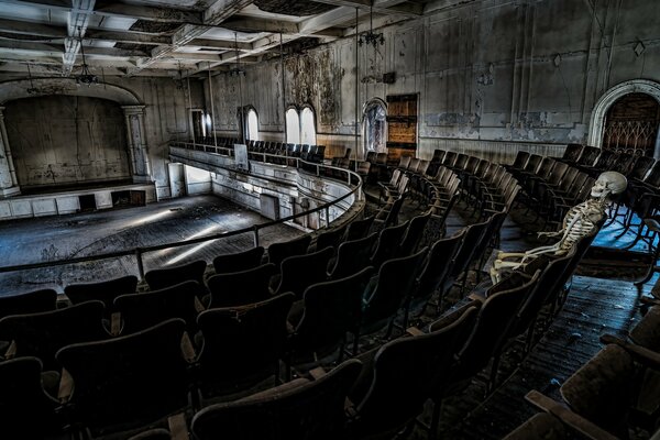 A skeleton sits in the stands of an old abandoned theater