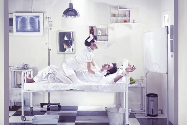 A nurse in a ward on a bed with a patient