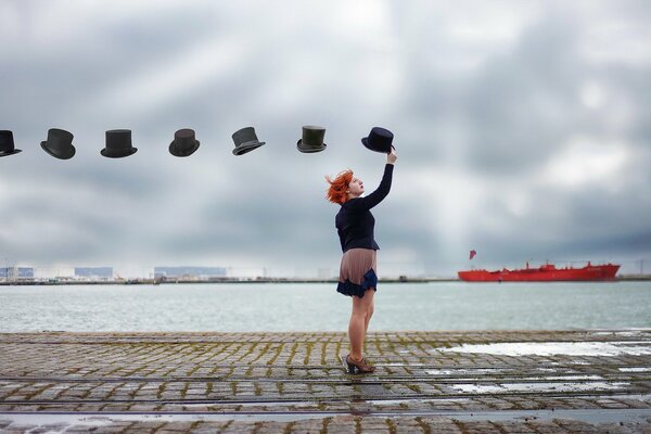 Ragazza con i cappelli al molo