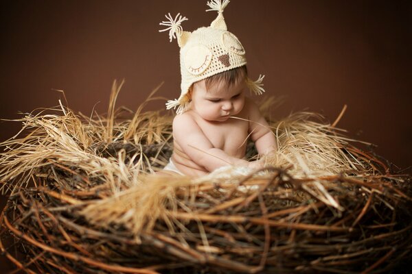 Малыш с шапочкой совы сидит в гнезде