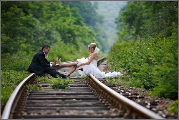 The bride and groom decided to make a beautiful shooting in the woods on the train tracks