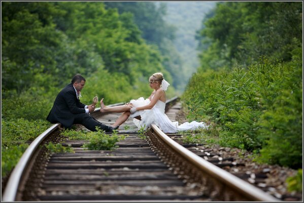 El novio y la novia decidieron hacer un hermoso disparo en el bosque en los rieles del tren