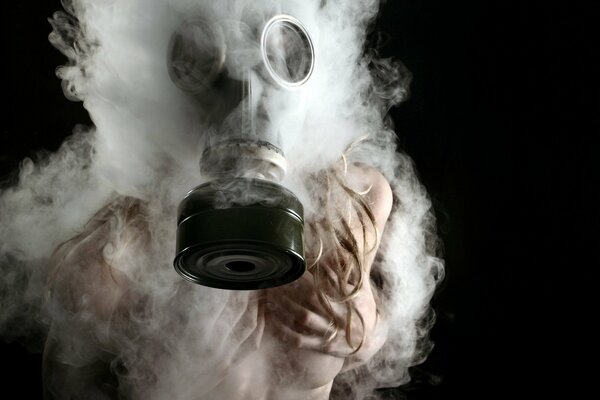 La jeune fille dans un masque à gaz contre la fumée