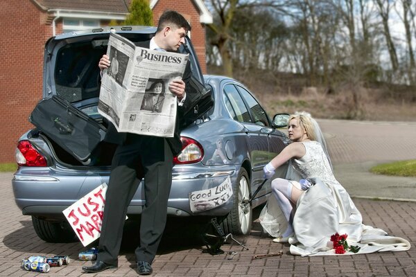 Das Mädchen repariert das Auto und der Kerl liest die Zeitung