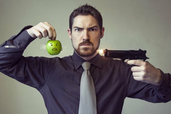 Ein Mann mit einer Pistole und einem Apfel. Inszeniertes Foto