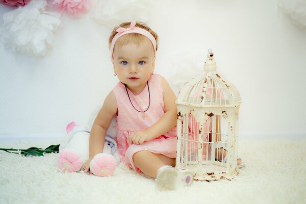 Dziewczynka w różowej sukience z klatką dla ptaków