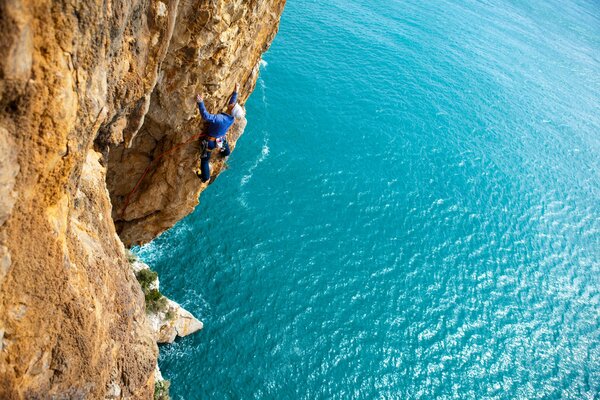 Ein Bergsteiger klettert auf einen Felsen über dem Meer