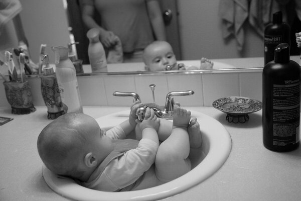 Bambino che fa il bagno in un lavandino carino