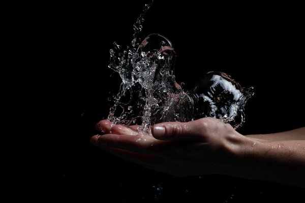 La main avec des projections d eau sur fond noir