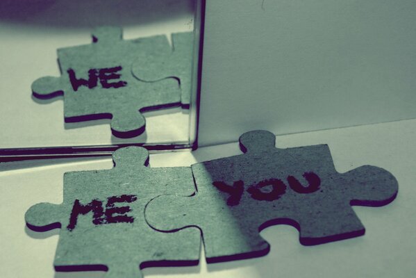 A couple of puzzle pieces with a reflection in the mirror and the words we I you in English