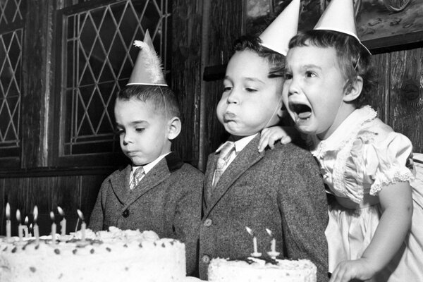 Dzieci zdmuchują świece na torcie urodzinowym
