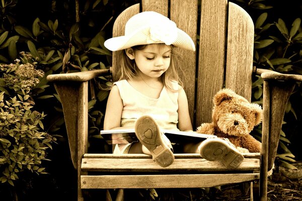 La petite fille garde-le sur la chaise avec le livre de m de l ours