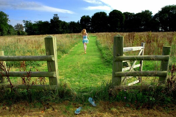 A running girl in a field and a wooden fence