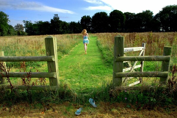 Chica corriendo en el campo y cerca de madera