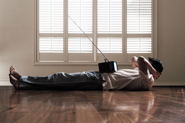 A man lying on the floor watching TV