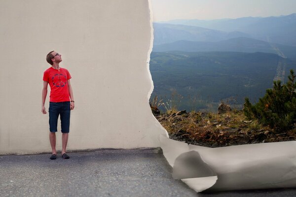 Ein Mann im roten T-Shirt schaut in der Nähe einer weißen Wand zum Himmel