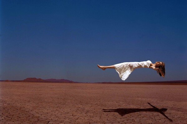 El vuelo de una niña sobre el desierto contra el cielo