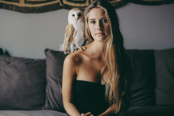 A girl with a white owl on her shoulder